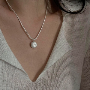 Close-up of S925 sterling silver chain with a baroque pearl pendant on a model's neck
