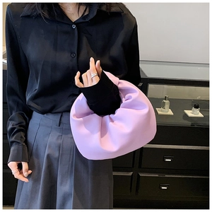Detail of purple knotted handle cloud bag paired with grey pleated skirt on model