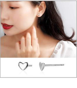 Macro detail of S999 sterling silver heart studs showing material stamp and ear worn effect