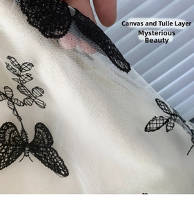 Detail of canvas bag with delicate butterfly lace embroidery over sheer mesh layer
