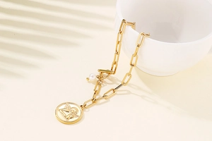 Detail of gold paperclip chain necklace with angel coin pendant and small pearl accent