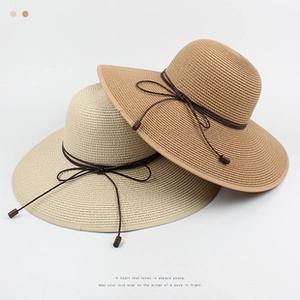 Detailed view of woven straw sun hats in beige and camel colors with decorative ties