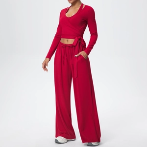 Détail d'un haut rouge à manches longues croisé et d'un pantalon large à taille haute