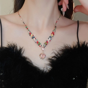 Detail of V-shaped gold necklace set with colorful zircons and pink heart pendant