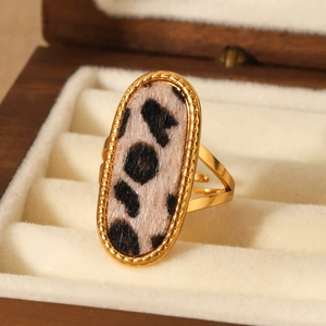 Golden stainless steel leopard print ring with adjustable band on a wooden jewelry box