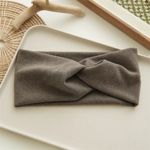 Détail d'un bandeau en maille marron avec nœud, posé sur un plateau beige épuré