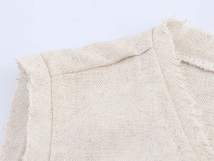 Detailed close-up showing the raw hem edge and linen texture of the beige vest