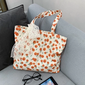 Close-up of canvas tote bag with orange print, white lace ribbon and large capacity