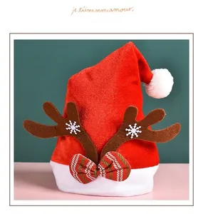Detail of red plush Christmas hat with brown reindeer antlers and a festive striped bow tie