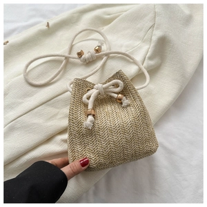 Detail of hand-woven straw bucket bag with cotton drawstring closure and textured wood finish