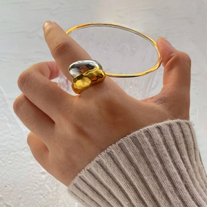 Detail of two-tone gold and silver ring with irregular fluid design on hand
