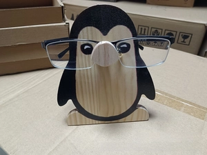Close-up of penguin-shaped wooden glasses holder with printed pattern on office desk