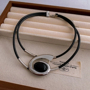 Detail of silver spiral pendant with black oval gemstone on leather cord in a jewelry box