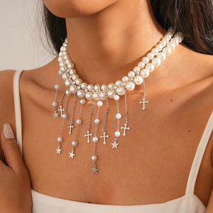 Détail d'un collier de perles à double rangée avec étoiles et croix argentées