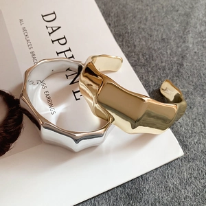 Detail view of irregular liquid metal open bangles in polished gold and silver finishes