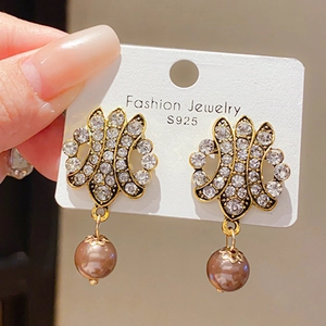 Détail macro de boucles d'oreilles vintage en or torsadé avec cristaux et perles brunes