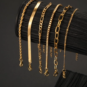 Detail of six assorted gold chain bracelets including snake and curb styles on a black display