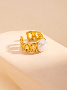 Detail of gold chain-style adjustable ring with square white gemstone on a display stand
