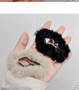 Detail of plush faux fur hair clips in beige and black with soft velvet texture