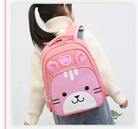 Vista posteriore di un bambino con uno zaino in tela rosa con un simpatico cartone animato