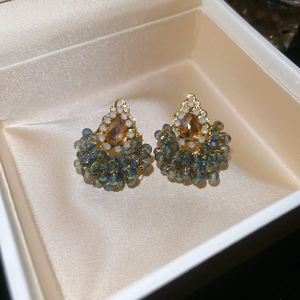 Vue détaillée des boucles d'oreilles goutte ambre avec cristaux gris-bleu sur satin