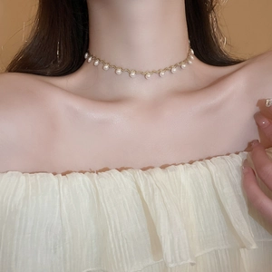 Close-up of elegant gold wavy choker necklace with white pearls on a female model neck