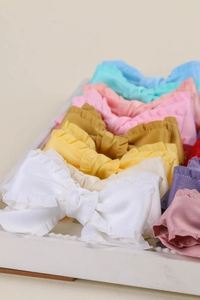 Gros plan de nœuds en ruban de satin à volants de couleurs variées sur un plateau