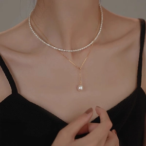 Detail of a gold layered necklace featuring lustrous white pearls on a minimalist Y-chain