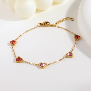 Dettaglio di un bracciale placcato oro con cinque zirconi rosa a forma di cuore chic