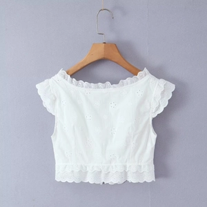 Détail d'un crop top blanc en broderie anglaise avec fleurs et ourlet ondulé chic
