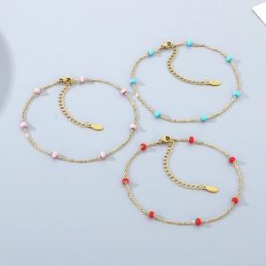Detailed view of three gold stainless steel anklets with pink, blue, and red enamel beads