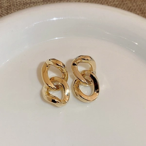 Elegant gold double interlocking geometric loop earrings displayed on ceramic tray