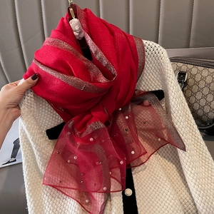 Detail of red faux silk scarf with gold lurex stripes and elegant pearl bead trimmings