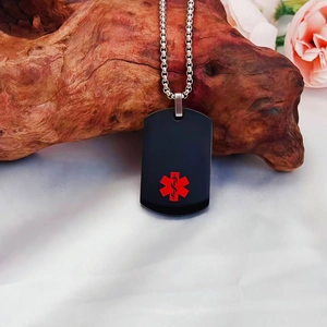 Dettaglio macro della piastrina medica nera in acciaio con simbolo Star of Life rosso
