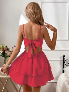 Detail of red backless cotton dress featuring a large elegant bow and layered skirt