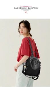 Side view of black PU leather travel backpack with a cartoon charm on a model