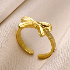 Detailed view of an adjustable gold bow ring on soft silk fabric for women