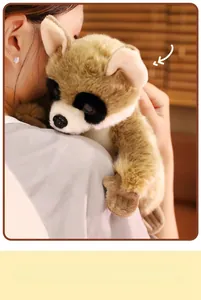 Close-up of cute plush lemur doll with fluffy fur and big eyes held by a person