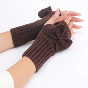 Detailed knit texture and large bow on dark brown fingerless gloves worn by a model