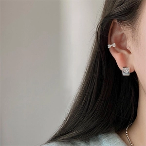 Model wearing sterling silver heart earring and bow ear cuff with white zirconia stones