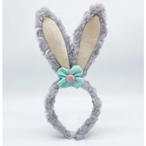 Detail of plush grey rabbit ears headband featuring a mint green bow and pink button