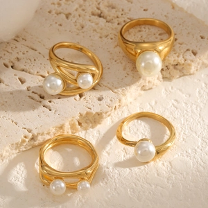 Minimalist gold-plated titanium rings with white pearls displayed on natural stone