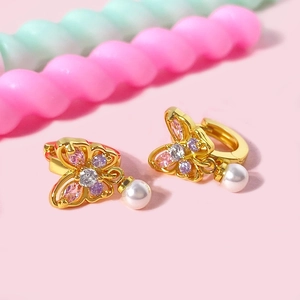 Gros plan de boucles d'oreilles papillon dorées avec zircons et perles blanches
