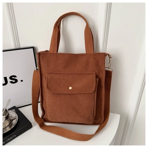 Detail of brown corduroy shoulder bag with adjustable strap and front pocket on white surface