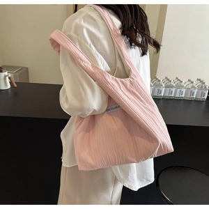 Detailansicht der rosa gefalteten Nylon-Tasche mit dem Kiss Yourself-Etikett