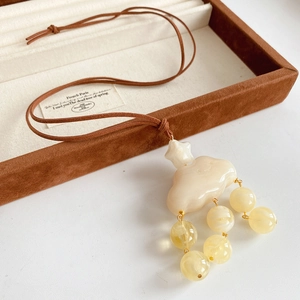 Macro detail of resin cloud pendant with star and yellow beads on leather cord necklace