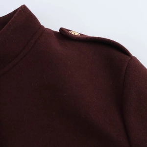 Détail de l'épaule d'une veste en laine bordeaux avec épaulette et bouton doré