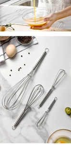 Detailed macro of stainless steel whisk set with spring handles on marble surface