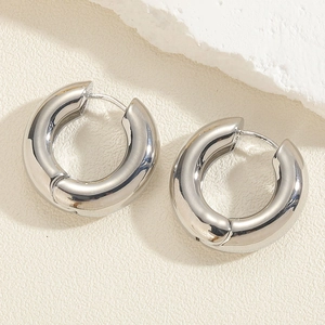 Detailed macro view of polished silver C-shape thick hoop earrings on stone background