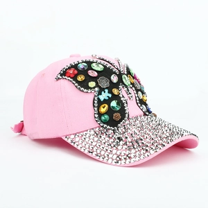 Détail d'une casquette rose avec papillon en strass et rivets métalliques argentés